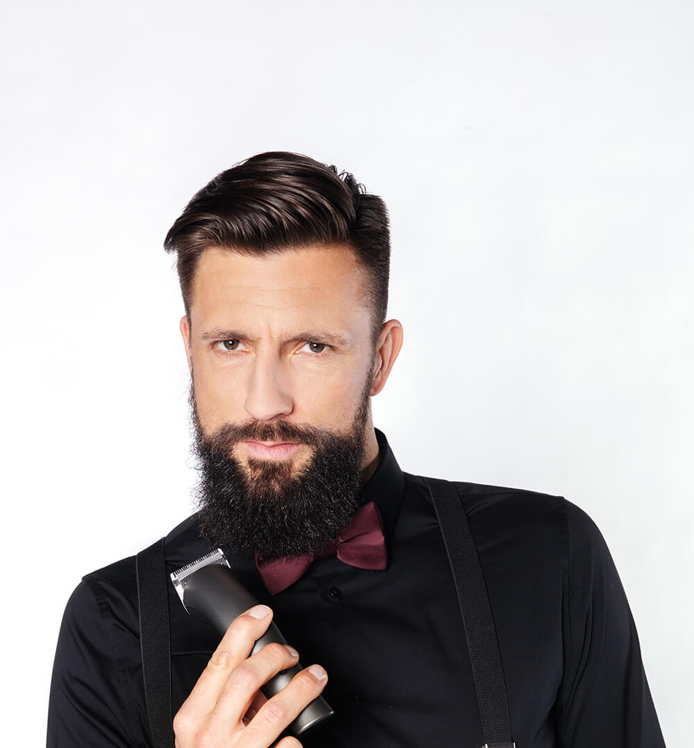 mann-mit-kurzen-dunkelbraunen-haaren-und-vollbart-mit-haarschneidemaschine-in-hand