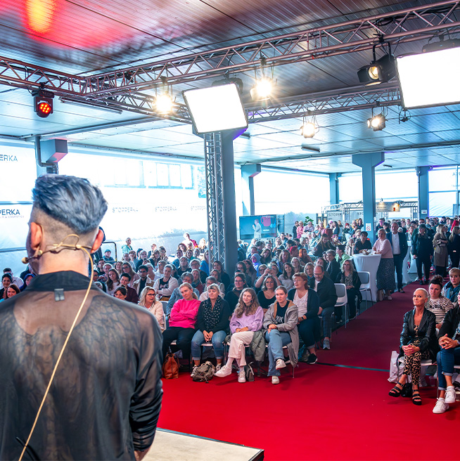 ueber_uns_bild_hausmesse_mit_buehne_und_publikum_stopperka