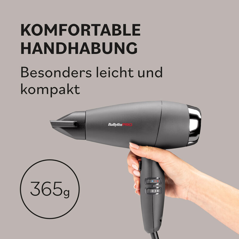 Hand hält den kompakten grauen BaBylissPRO Evoluto Haartrockner mit Stylingdüse und einer Gewichtsangabe von 365 Gramm