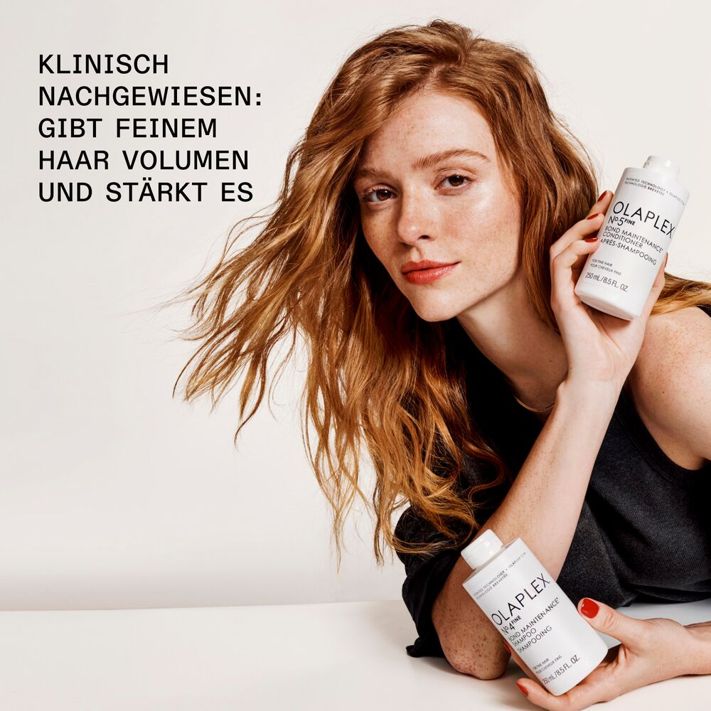 olaplex-volumenpflege-fuer-feines-haar-klinisch-bestaetigt-rothaarige-frau-mit-shampoo-und-conditioner-flaschen